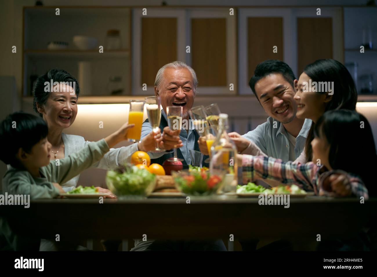 Eine asiatische Familie aus drei Generationen zu Hause, die den Urlaub mit einem Toast feiert Stockfoto