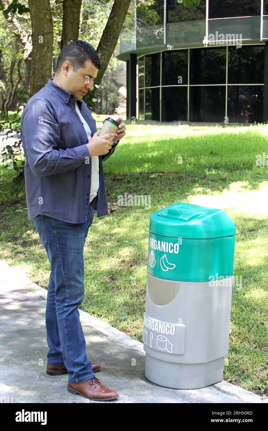 Der dunkelhaarige Erwachsene Latino-Mann wirft seine Tasse Kaffee in einen  Mülleimer, wobei organischer und anorganischer Abfall getrennt werden  Stockfotografie - Alamy