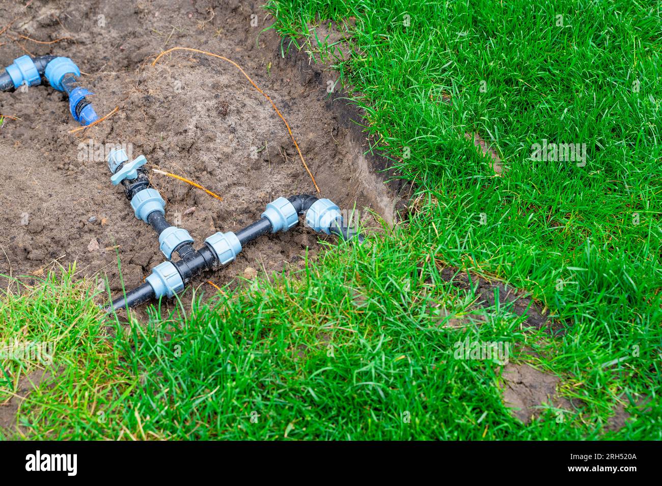 Kunststoffrohre und Stromkreisverkabelung für die Rasenbewässerung. Anschlussarmaturen und Ventile zum Absperren von Wasser im Garten Stockfoto