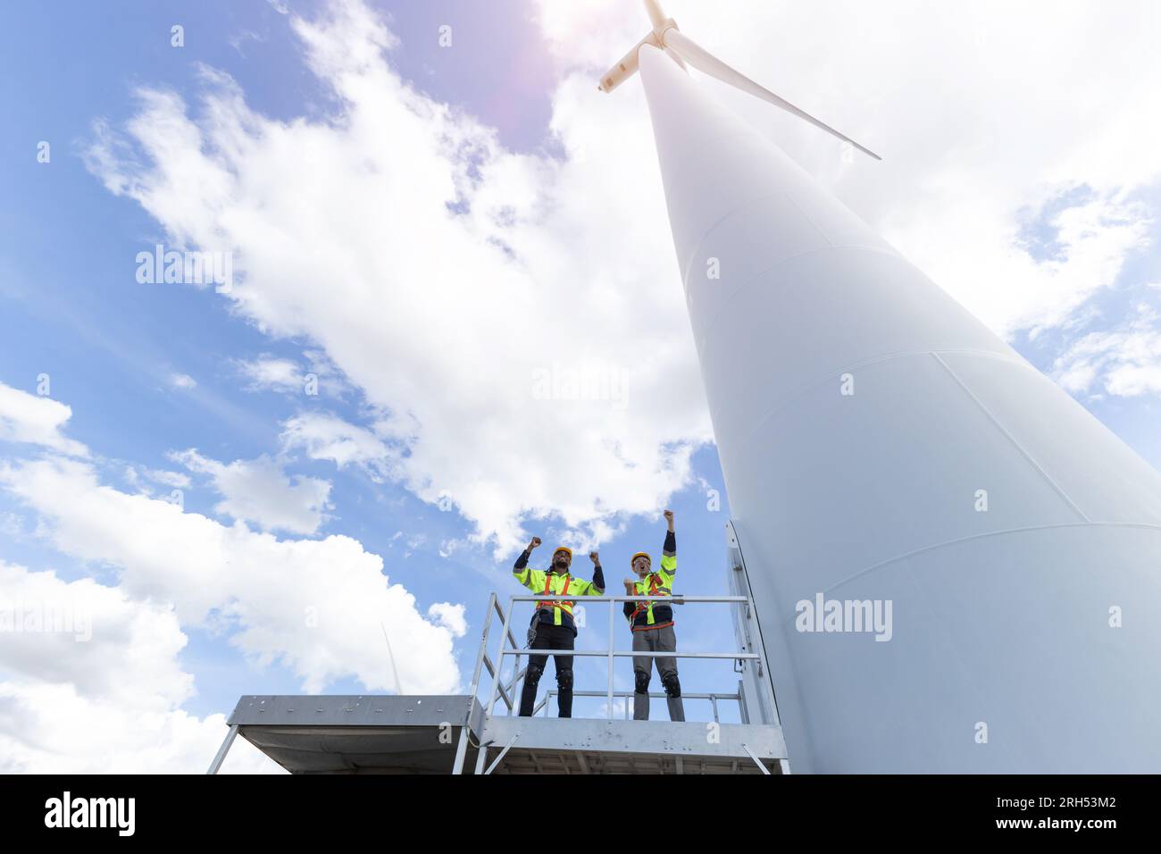 Ein erfolgreiches Technikerteam hob nach Abschluss der Arbeiten gerne die Hände und baute eine neue Infrastruktur für umweltfreundliche Energie aus Windkraftanlagen Stockfoto