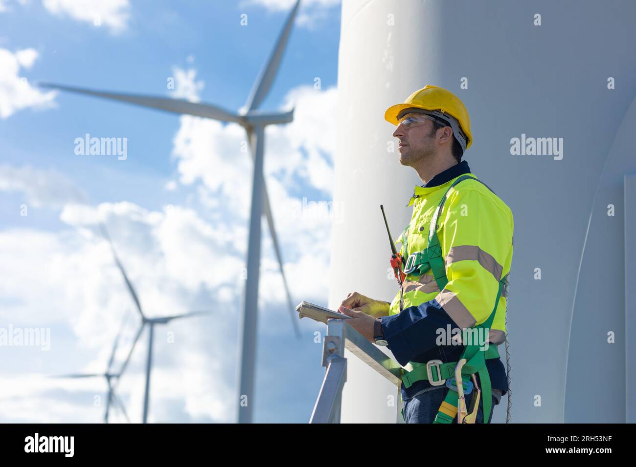 Das Serviceteam männlicher Windturbines, der selbstbewusster Ingenieur, blickt nach oben auf die Zukunft des Konzepts für saubere Energie Stockfoto