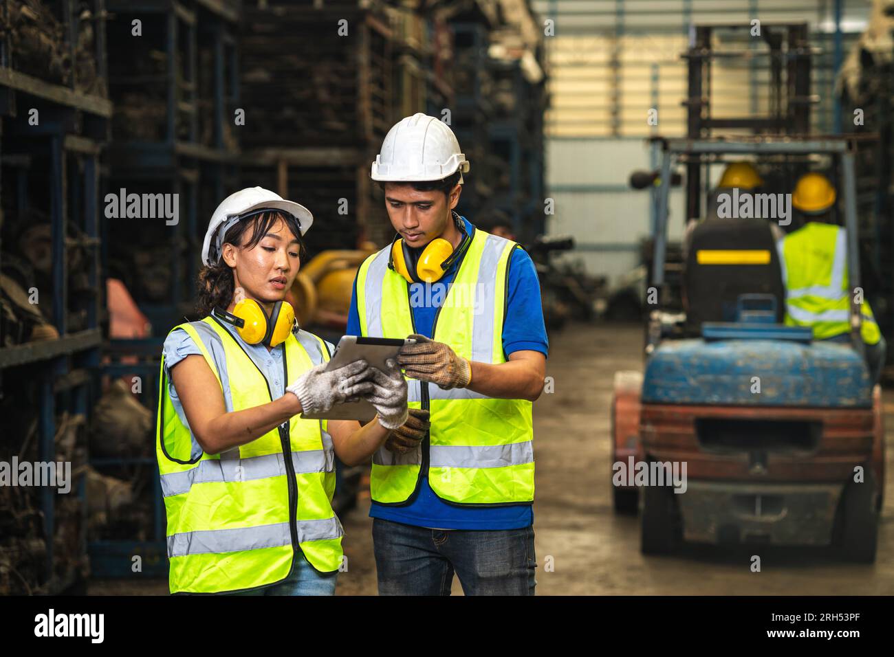 Ingenieurmitarbeiter-Team Frauen arbeiten zusammen mit Mann arbeiten auf einem schmutzigen Schrottplatz, altes Lager für Autoteile, die recycelt oder repariert werden sollen Stockfoto