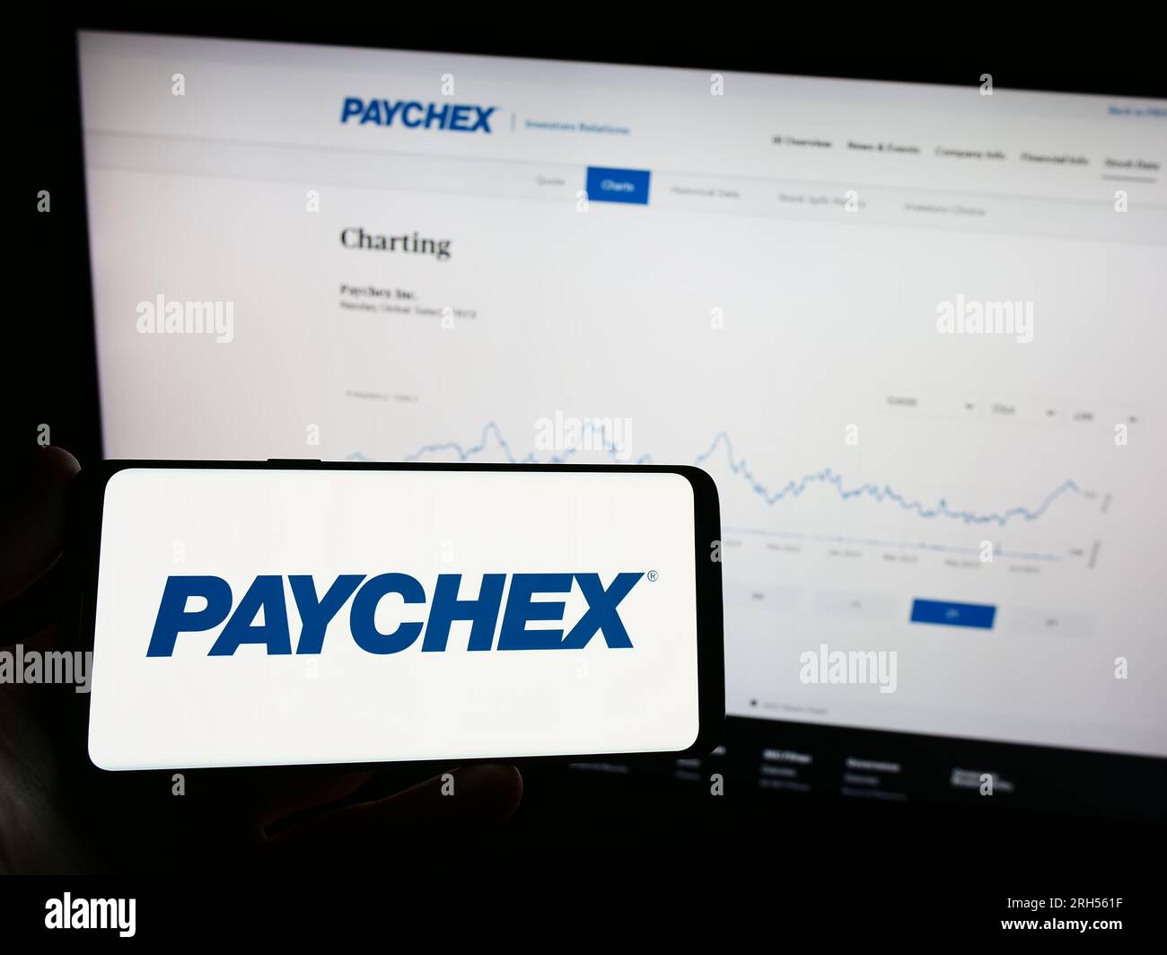 Person, die ein Mobiltelefon mit dem Logo des amerikanischen Outsourcing-Unternehmens Paychex Inc. Auf dem Bildschirm vor der Webseite hält. Konzentrieren Sie sich auf das Display des Telefons. Stockfoto