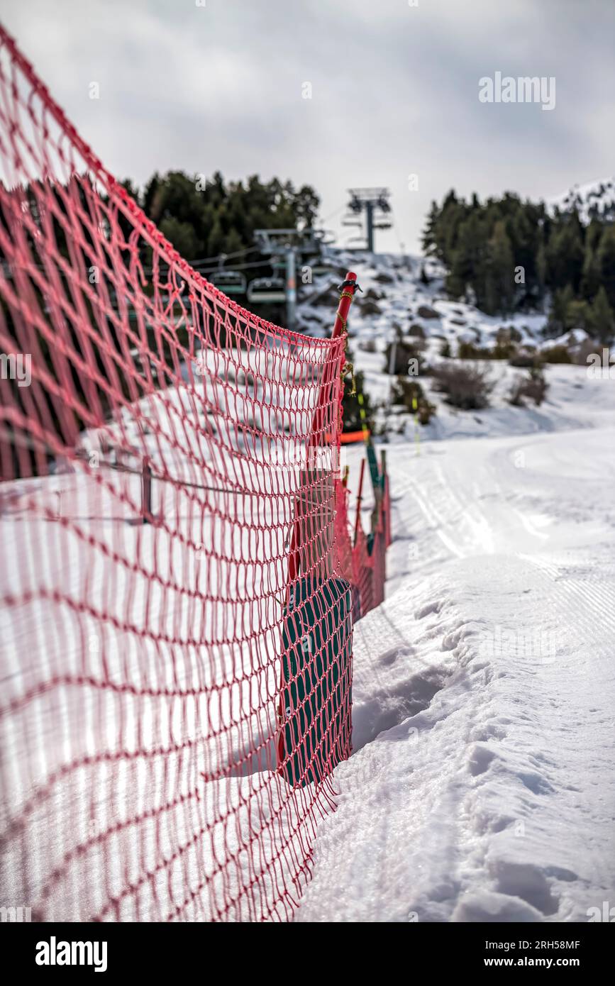 Ein Detail der orangefarbenen Plastikbarriere auf der Skipiste Stockfoto