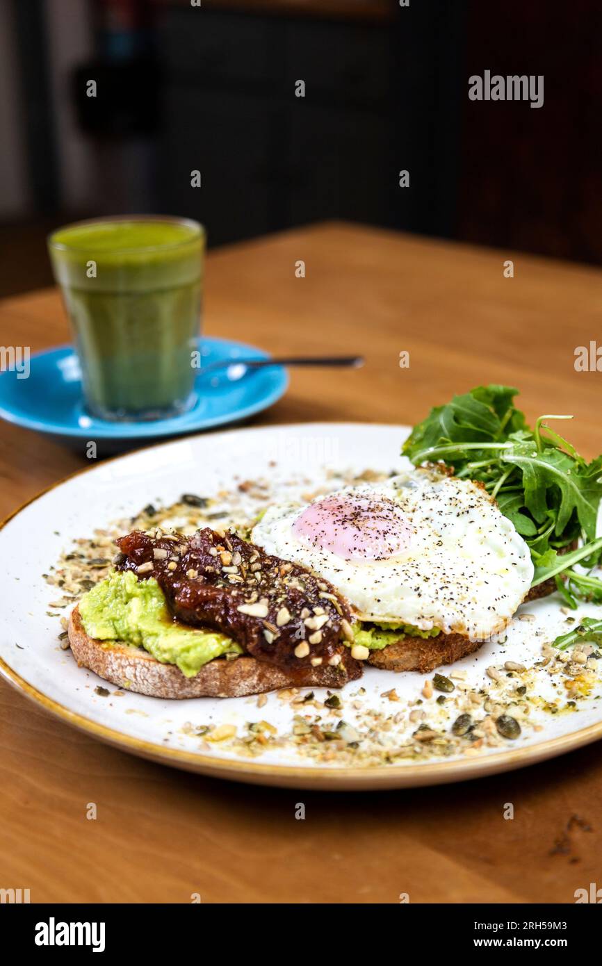 Zerkleinerte Avocado auf Sauerteigbrot mit Ei, Chutney und Dukkah im Stables Cafe bei Orleans House Gallery, Twickenham, London, England Stockfoto