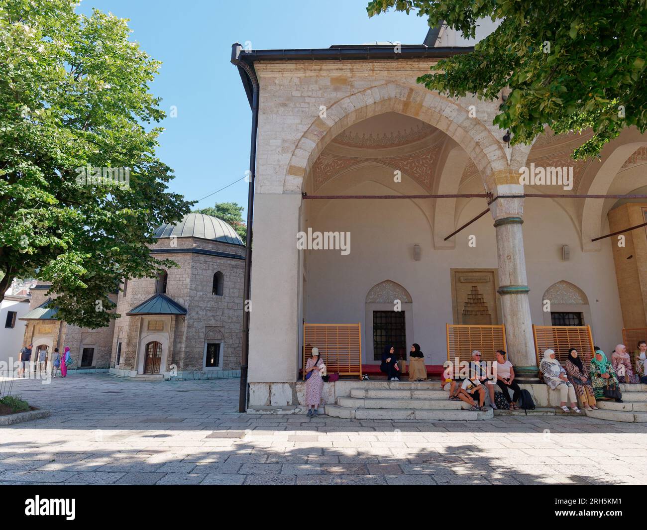 Frauen sitzen vor der Gazi Husrev-Beg Moschee, einer Osmanischen Moschee aus dem 16. Jahrhundert, Sarajevo, Bosnien und Herzegowina, 13. August 2023. Stockfoto