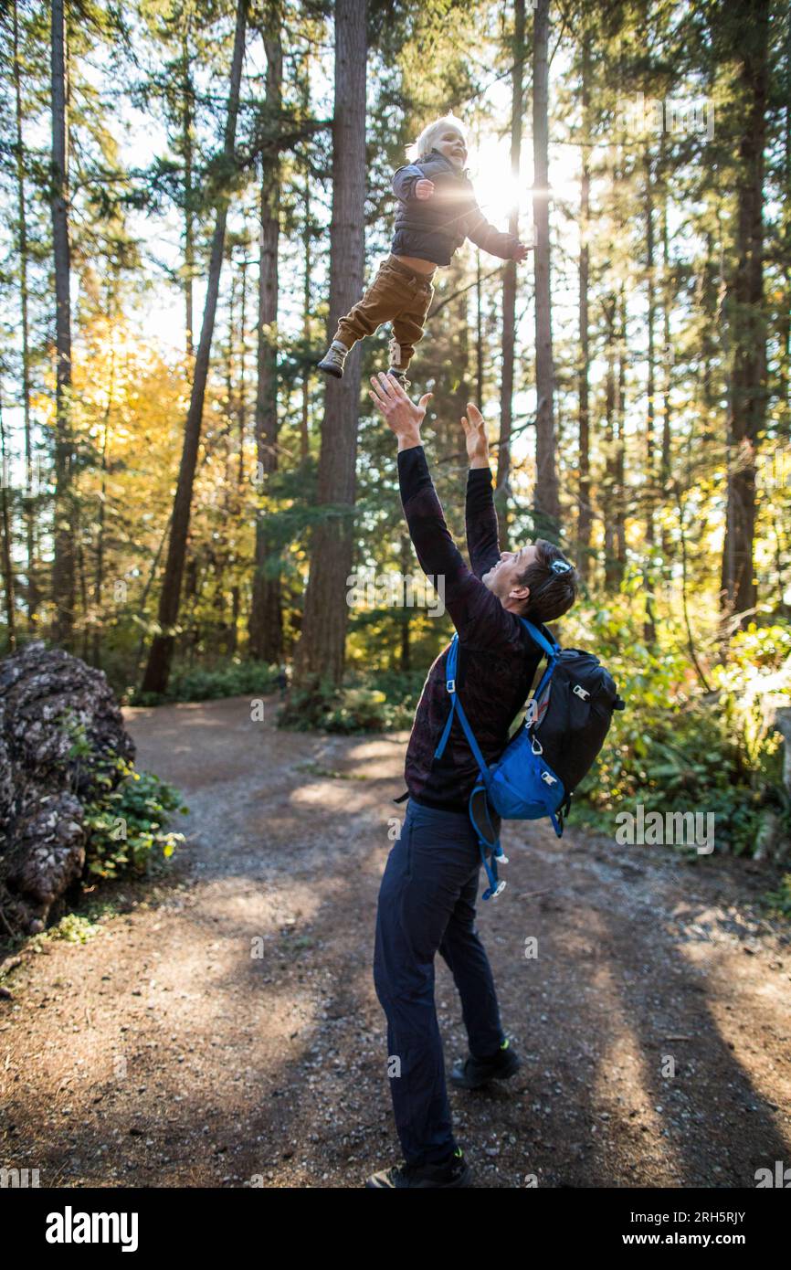 Vater hebt die Arme, um seinen Sohn zu fangen, der mitten in der Luft fliegt. Stockfoto