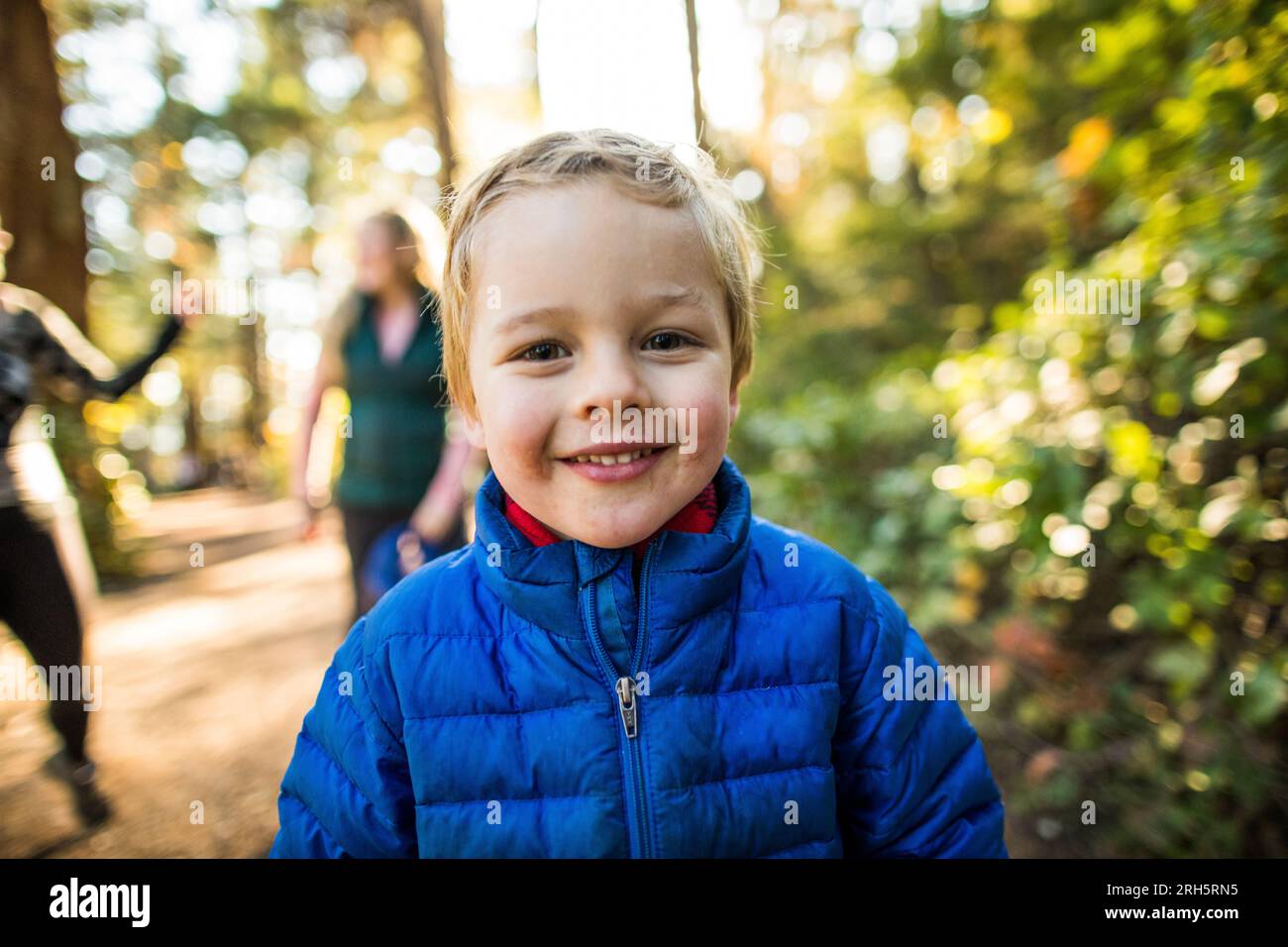 Porträt eines jungen glücklichen Kindes im Freien mit blauer Jacke Stockfoto