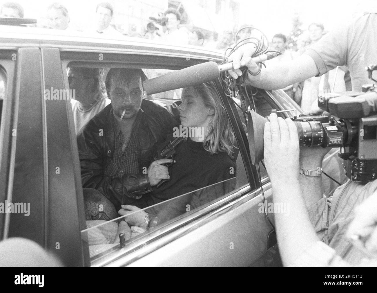 ARCHIVFOTO: Vor 35 Jahren, am 16. August 1988, begann der Angriff auf eine Sparkasse-Filiale in Gladbeck, die Täter flohen tagelang mit Geiseln durch Deutschland, der Geiselnehmer Dieter DEGOWSKI hält die Geisel Silke BISCHOFF, einen Swithh & Wesson Revolver unter dem Kinn; links: Die Geisel Ines VOITLE; eine Filmkamera und ein direktionales Mikrofon, die die Situation aufzeichnen, ragt ins Bild; Bankraub, Geiselnahme in Gladbeck, am 18. August 1988 in Köln; Entführung, Flucht, Fluchtwagen, Medien, sensationeller Journalismus, Journalismus, Journalist, Verbrechen, Verbrechen, Gangster, Geisel gan Stockfoto