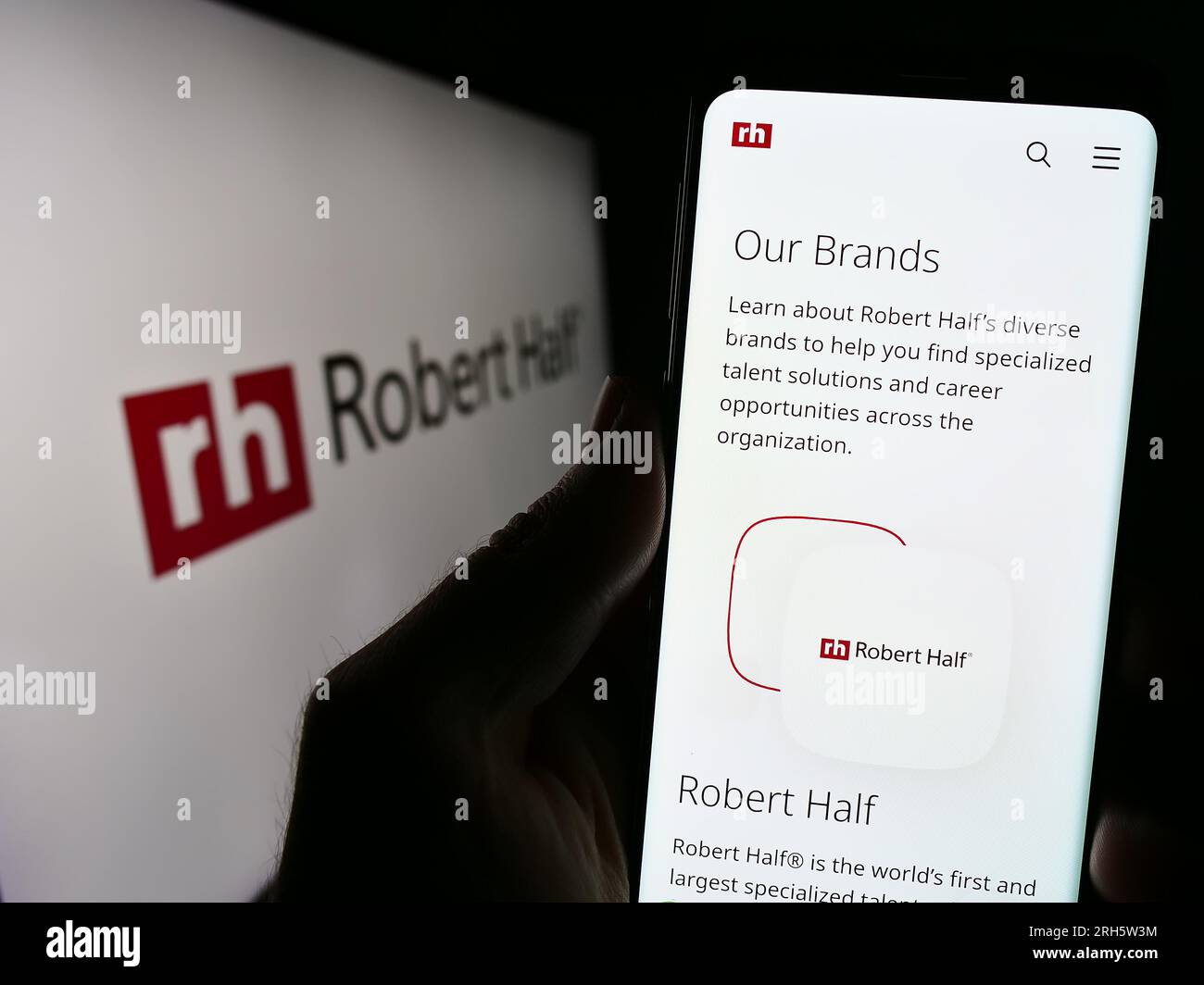 Person mit Smartphone und Website des US-Unternehmens Robert Half International Inc. Auf dem Bildschirm vor dem Logo. Konzentrieren Sie sich auf die Mitte des Telefondisplays. Stockfoto