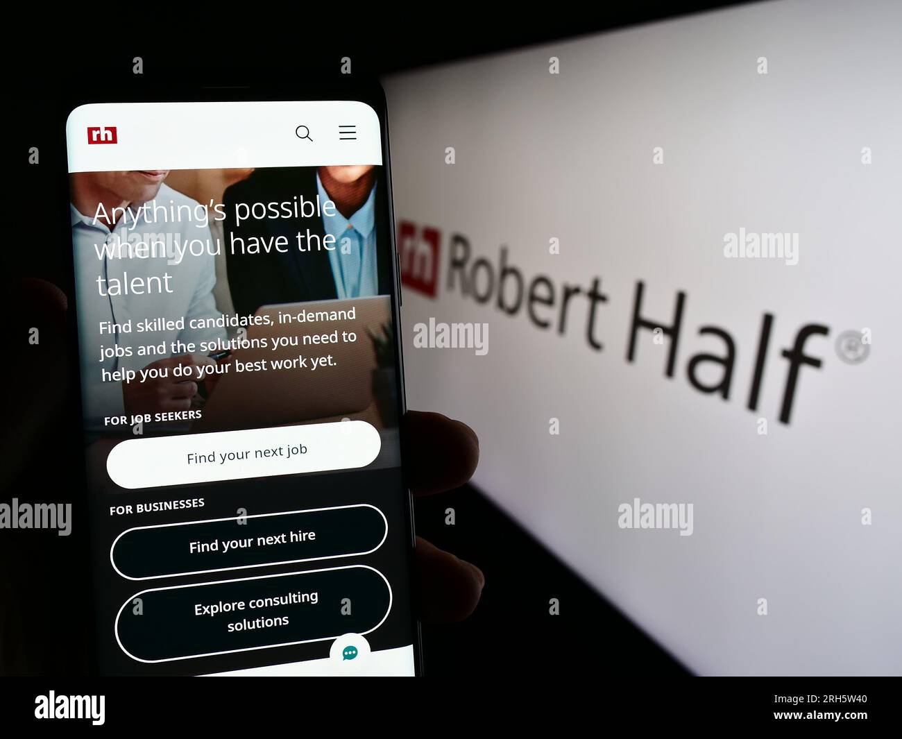 Person, die ein Mobiltelefon mit einer Webseite des US-amerikanischen Unternehmens Robert Half International Inc. Auf dem Bildschirm vor dem Logo hält. Konzentrieren Sie sich auf die Mitte des Telefondisplays. Stockfoto