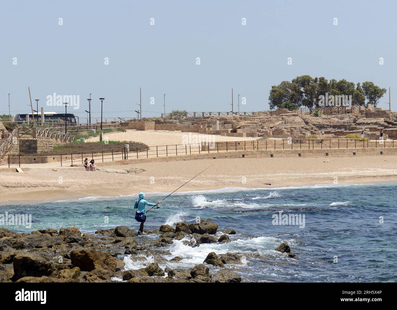 Ein Mann, der am Strand in der Nähe der römischen Ruinen in Cäsarea, Israel, anfischt. Stockfoto