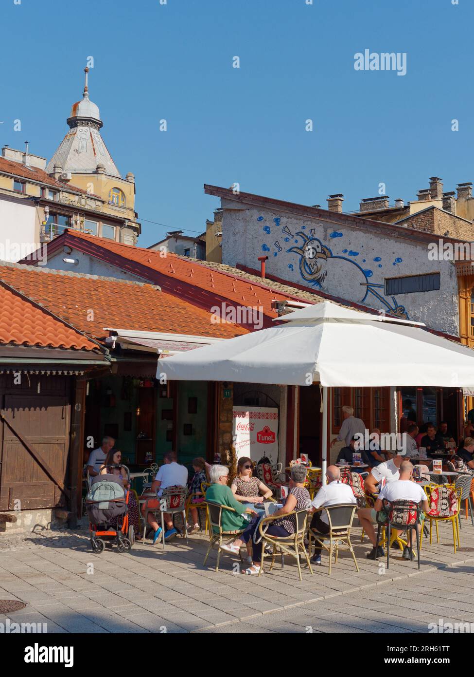Gäste in einem Café/Restaurant an einem Sommertag im Stadtteil Baščaršija in Sarajevo, Bosnien und Herzegowina, 14. August 2023. Stockfoto
