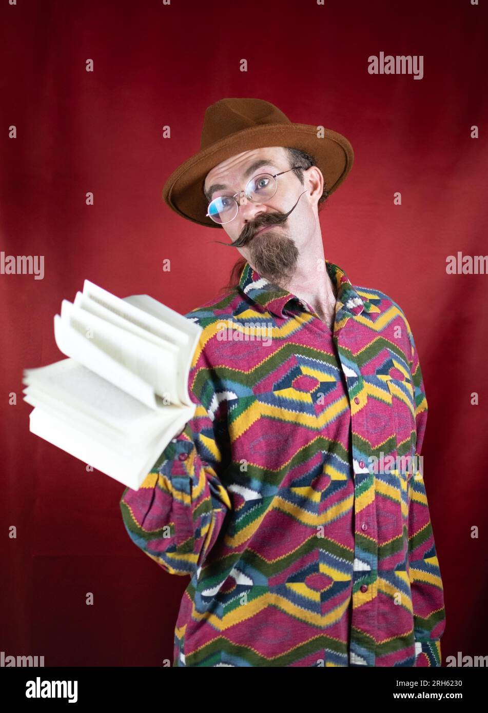 Vintage-Hipster-Mann mit Hut und Schnurrbart winkend Buch für verschiedene Konzepte Stockfoto