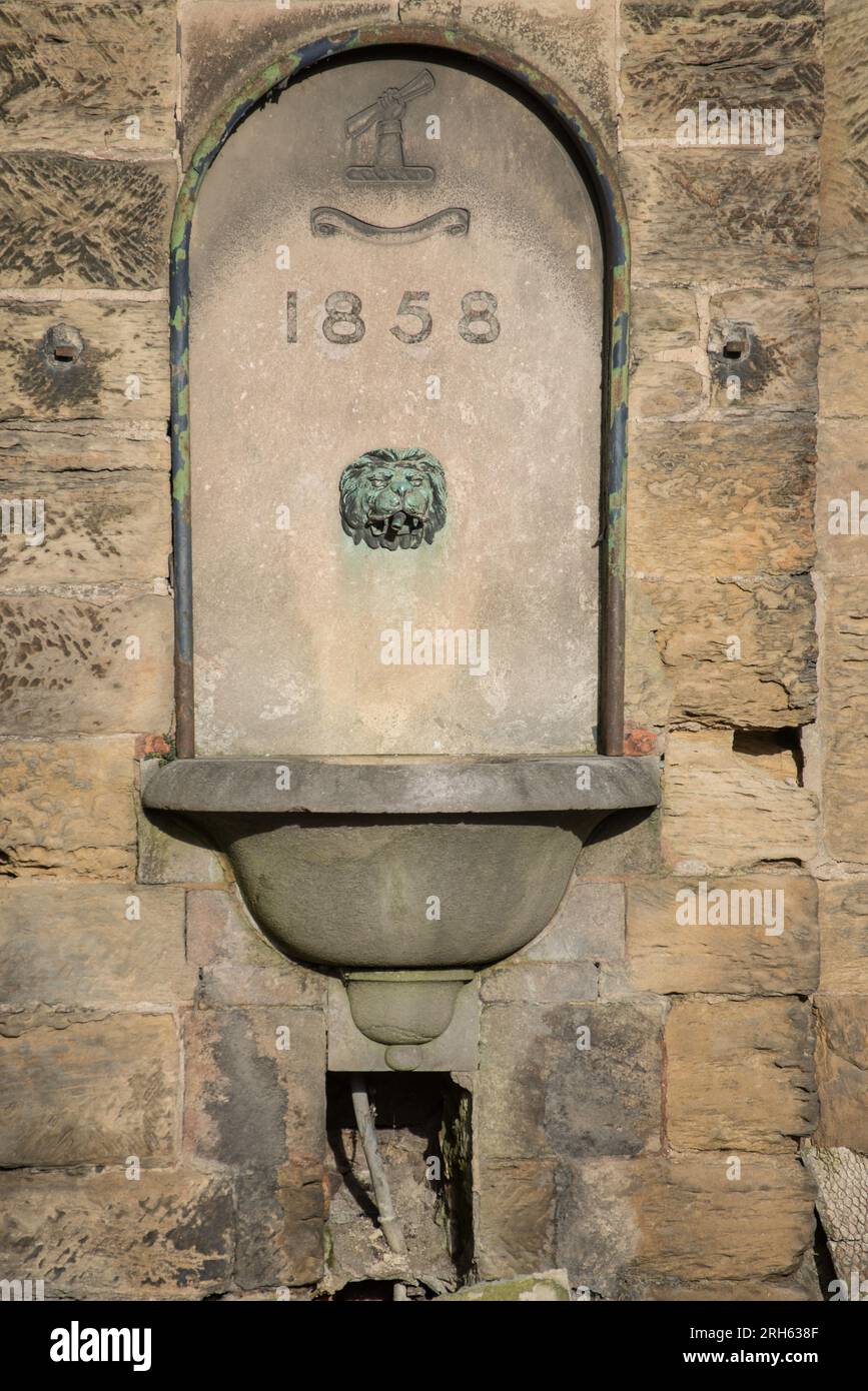 Viktorianischer Trinkbrunnen aus dem Jahr 1858 in Belper Derbyshire, England, mit Löwenkopf-Wasserhahn. Der Brunnen ist in die ältere Gangway Bridge von 1795 eingebaut Stockfoto