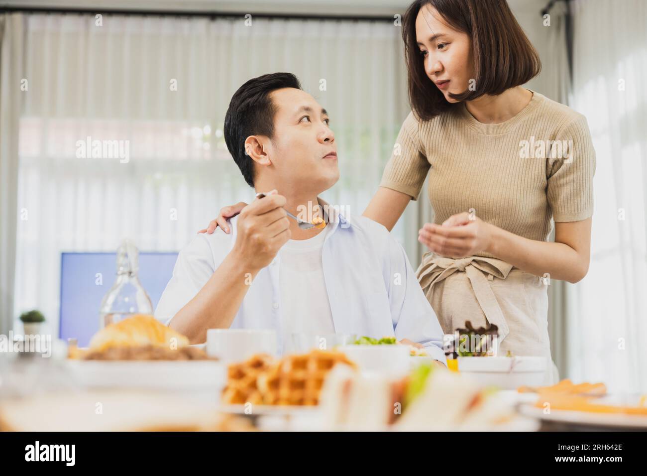 Asiatische Frau sprechen mit Mann beim Frühstück, glückliche Familie reden, bevor sie zur Arbeit gehen Stockfoto