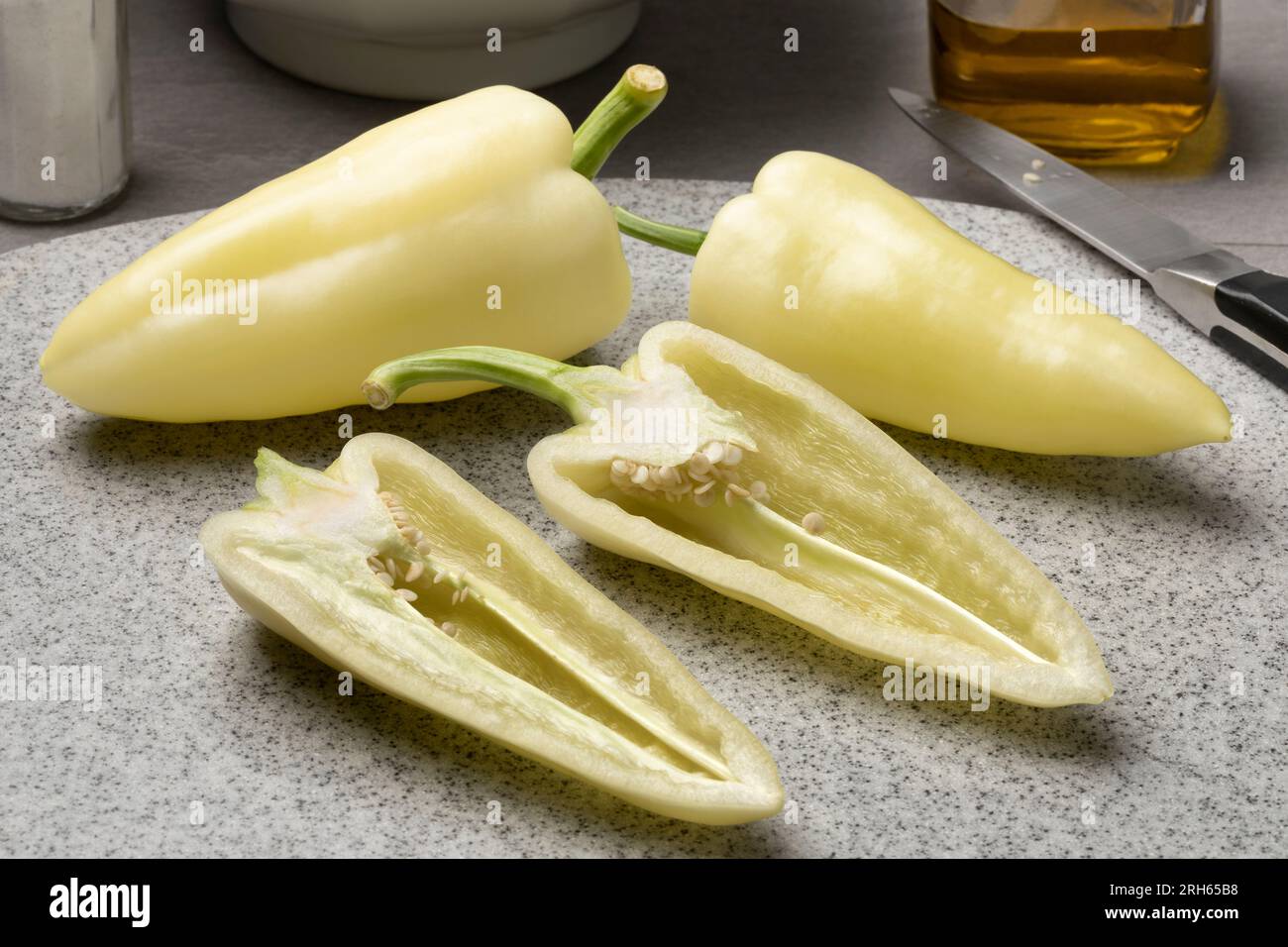 Ganze und halbierte frische rohe, spitze Paprika in Nahaufnahme Stockfoto