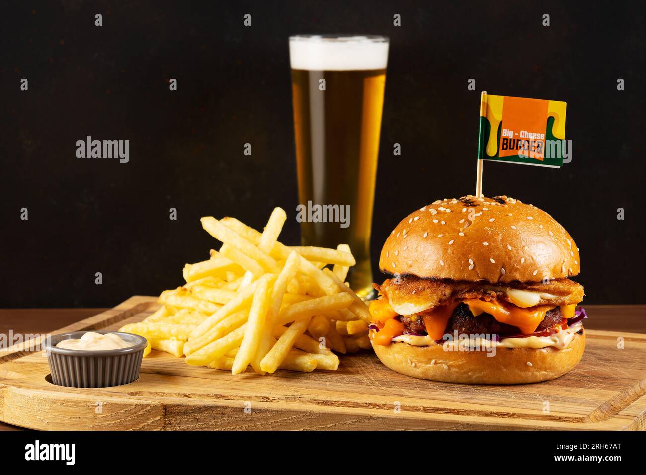 Fast-Food-Konzept. Leckerer Cheeseburger mit gebratenen Kartoffeln und einem Glas Bier auf einem Holztisch. Stockfoto