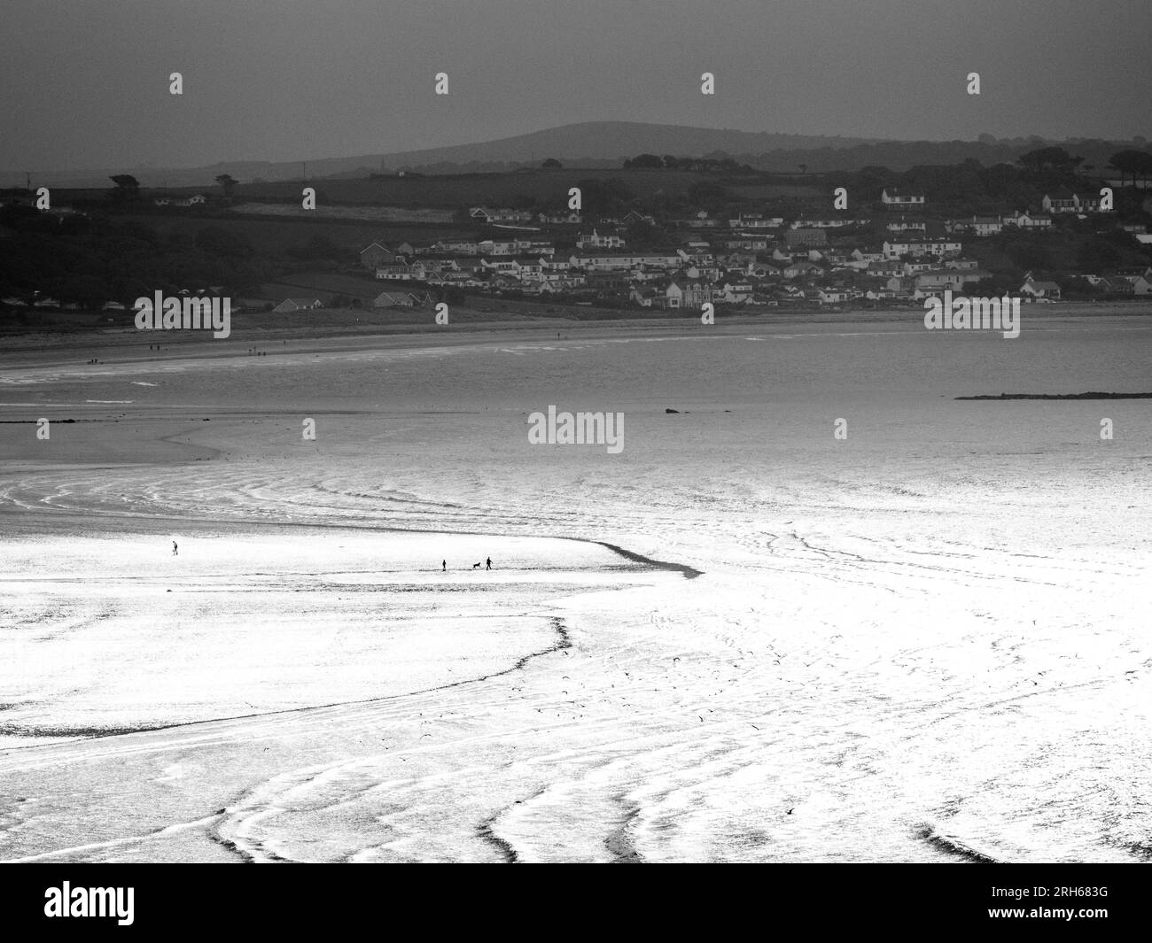Dramatic Light and Walkers on Long Rock Beach, Penzance, Cornwall, England, Großbritannien, GB. Stockfoto