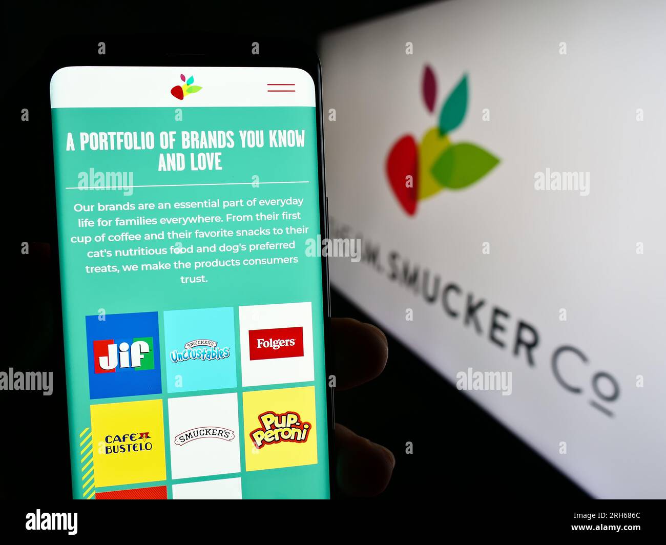 Person, die ein Smartphone mit einer Webseite des US-amerikanischen Lebensmittelgeschäfts The J.M. Smucker Company auf dem Bildschirm vor dem Logo hält. Konzentrieren Sie sich auf die Mitte des Telefondisplays. Stockfoto
