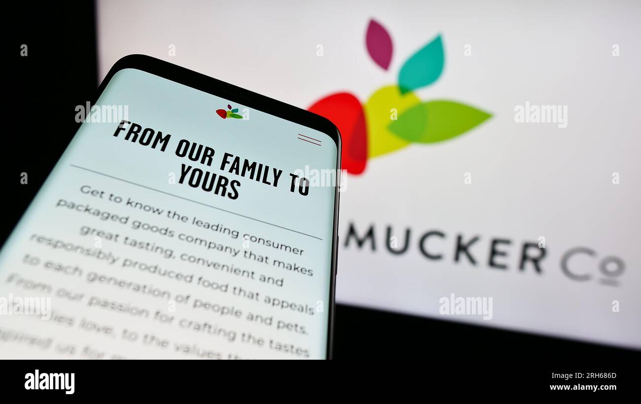 Mobiltelefon mit Webseite des US-amerikanischen Lebensmittelgeschäfts The J.M. Smucker Company auf dem Bildschirm vor dem Firmenlogo. Fokus auf oberer linker Seite des Telefondisplays. Stockfoto