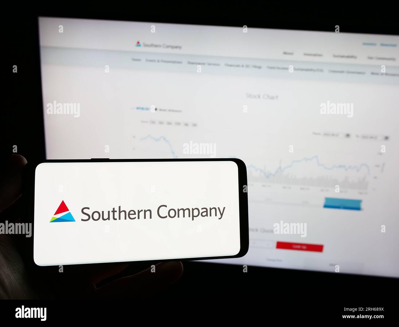 Person, die ein Mobiltelefon mit dem Logo des amerikanischen Versorgungsunternehmens Southern Company auf dem Bildschirm vor der Webseite hält. Konzentrieren Sie sich auf das Display des Telefons. Stockfoto