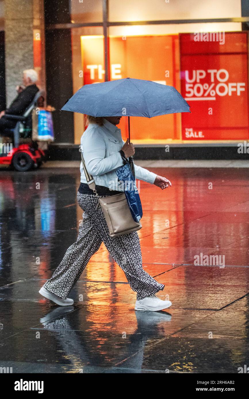 Southport, Merseyside. Wetter in Großbritannien. 14. August 2023; Wetter in Großbritannien. Um 19C Uhr regnet es warm, während die Käufer in Southport nass werden. Ausbrüche von Regenschauern in Nordengland und Wales heute Nachmittag, heftig und donnernd an einigen Stellen. Schwankende Wolken, sonnige Zauber und verstreute Schauer im Nordwesten. Kredit; MediaWorldImages/AlamyLiveNews Stockfoto