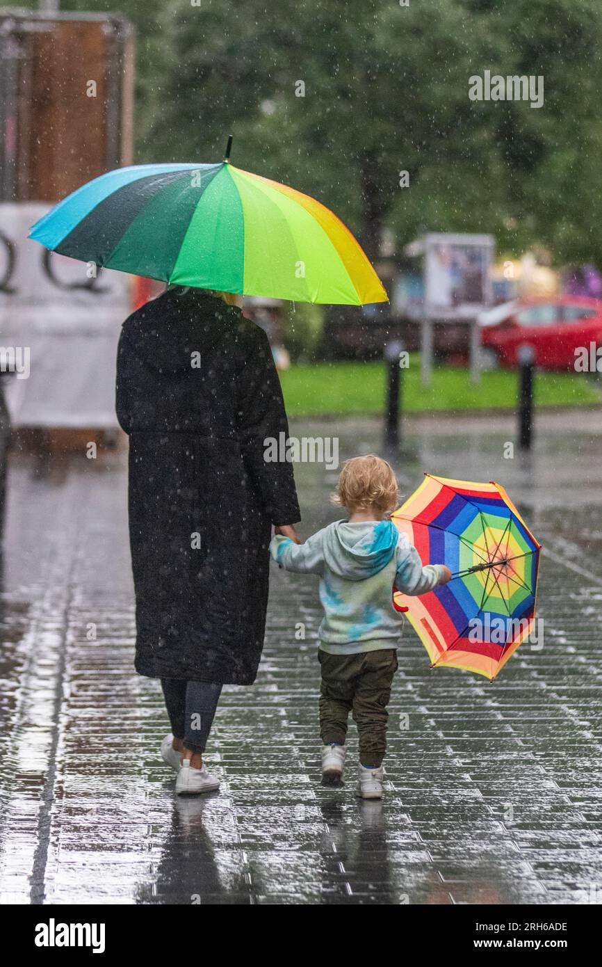 Mutter mit Kind, das einen Schirm hält, in Southport, Merseyside. Wetter in Großbritannien. August 2023; Wetter in Großbritannien. Warmer Regen um 19 °C, während die Käufer in Southport durchnässt werden. Ausbrüche von Regenregen in Nordengland und Wales heute Nachmittag, stark und donnernd. Wechselnde Wolken, sonnige Wellen und verstreute Schauern im Nordwesten. Stockfoto