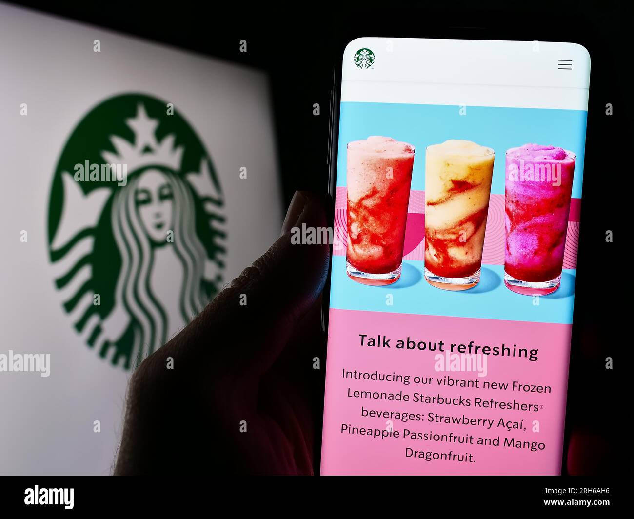 Person, die ein Mobiltelefon mit einer Website des US-amerikanischen Kaffeehausunternehmens Starbucks Corporation auf dem Bildschirm mit Logo hält. Konzentrieren Sie sich auf die Mitte des Telefondisplays. Stockfoto