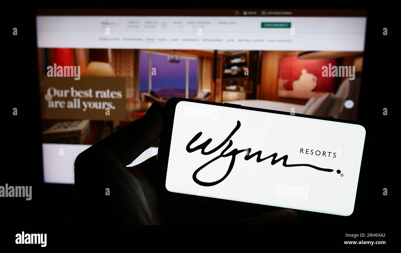Person, die ein Smartphone mit dem Logo des US-amerikanischen Hospitality-Unternehmens Wynn Resorts Limited auf dem Bildschirm vor der Website hält. Konzentrieren Sie sich auf das Display des Telefons. Stockfoto