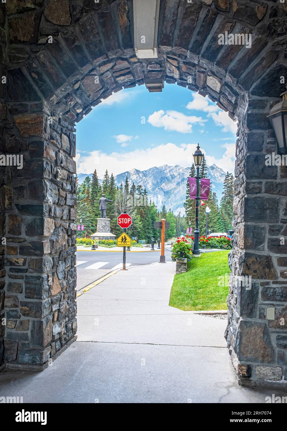 Blick auf das Gelände und die Rocky Mountains durch eine Steintür im Banff Springs Hotel. Stockfoto