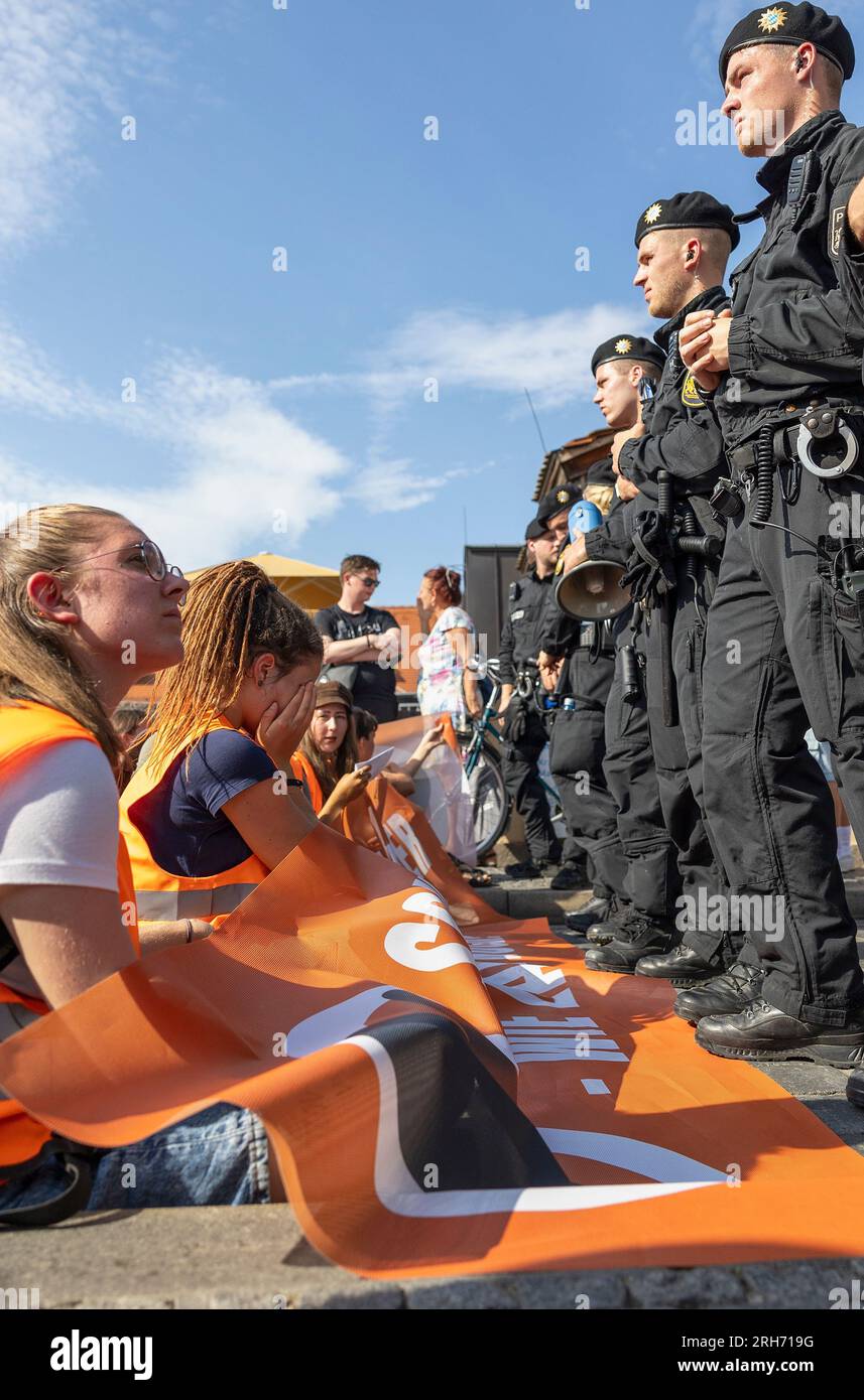 14. August 2023, Bayern, Würzburg: Die unter dem Namen Last Generation versammelten Menschen setzten sich vor die Polizeibarrikade auf der Alten Hauptbrücke, nachdem ein protestmarsch verboten wurde. Foto: Heiko Becker/dpa Stockfoto
