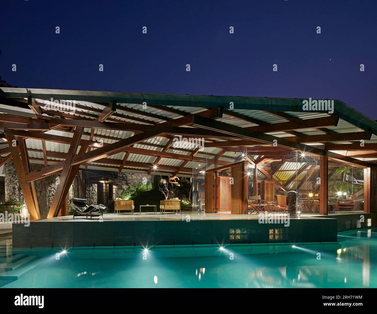 Außenansicht des neuen Flügels in der Abenddämmerung. Rückzug in den westlichen Ghats, Maharashtra, Indien. Architekt: Malik Architecture , 2021. Stockfoto
