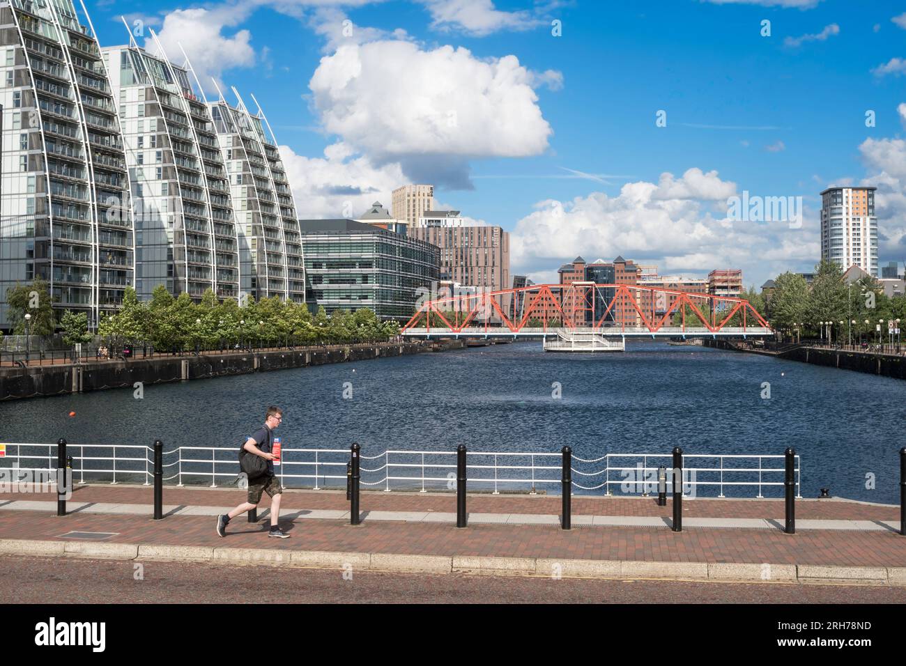 Ein Mann geht am Huron Basin und der Detroit Bridge in Salford Quays, England, vorbei Stockfoto