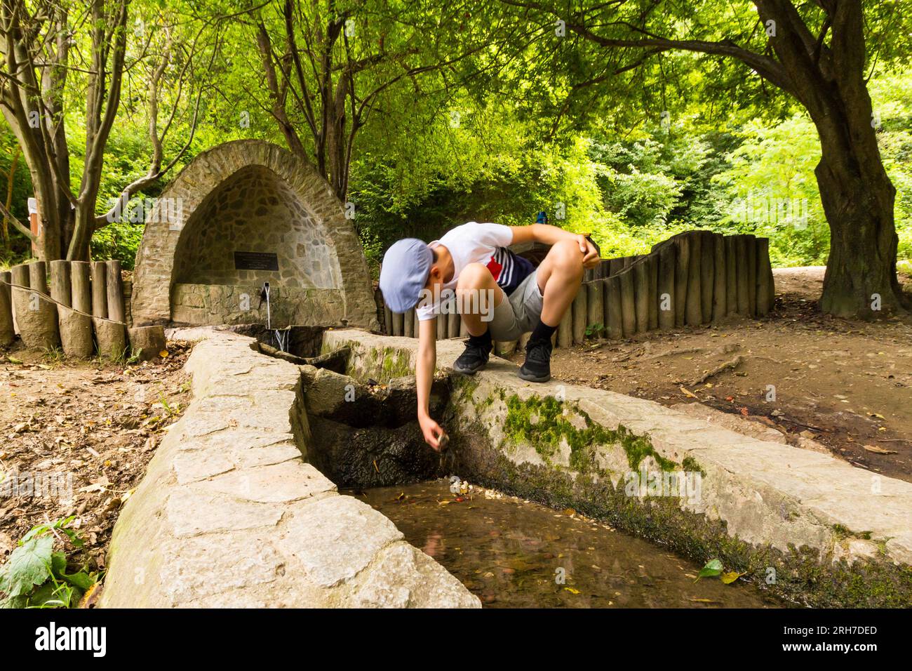 Ein Junge, der im Wasser spielt und aus Termeszetbarat-forras (Quelle) in der Nähe von Szalamandra-to, Sopron, Ungarn, kommt Stockfoto