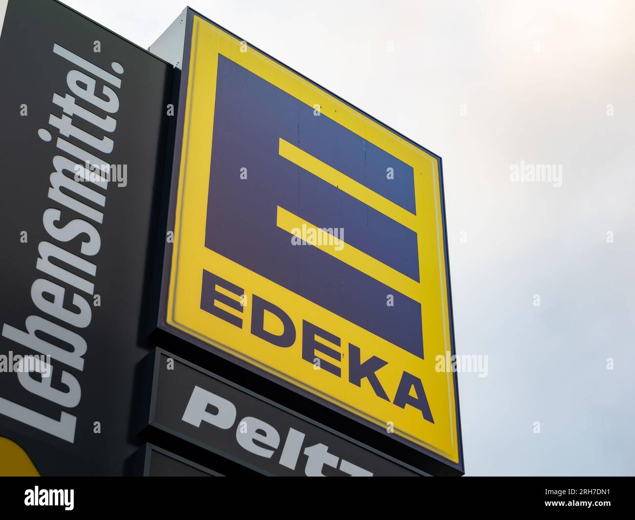Logo des Edeka-Lebensmittelgeschäfts als Werbung vor dem Himmel. Schilder für den deutschen Einzelhändler. Großer blauer E-Buchstabe auf Gelb. Stockfoto