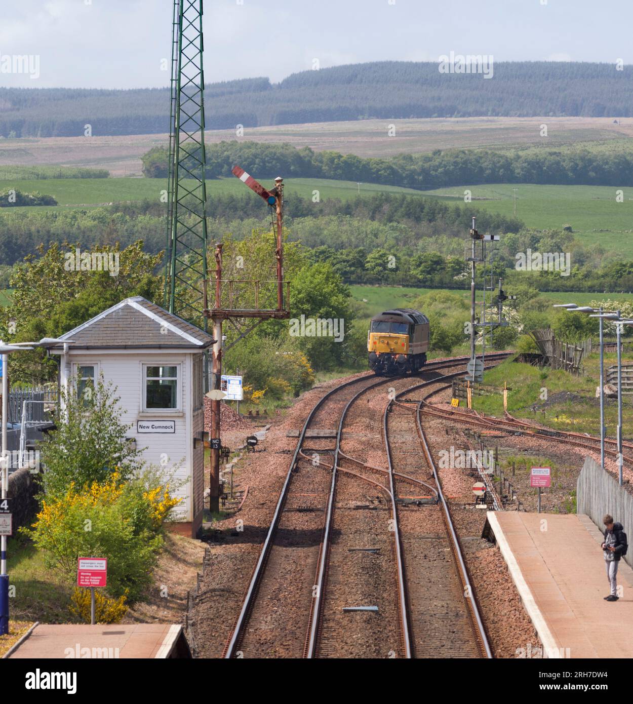 Lokomotive 47828 der Baureihe 47, die am mechanischen Stellwerk vorbeifährt, und am Semaphore-Signal mit hoher Halterung in New Cumnock, Ayrshire, Schottland, Großbritannien Stockfoto