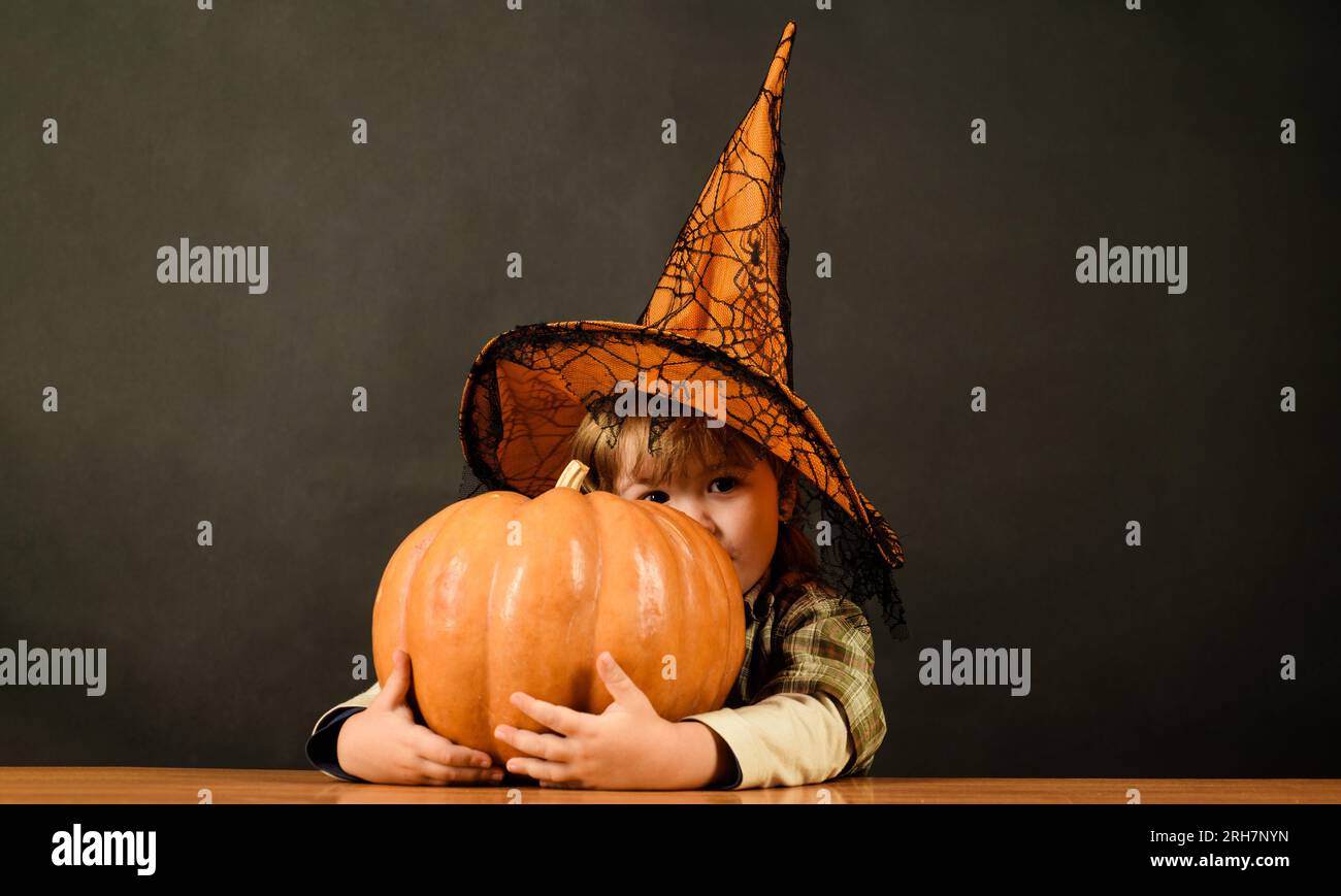 Halloween-Kinder. Lächelnder Junge mit Hexenhut und Halloween-Jack-o-Laterne. Ein kleines Kind im Zauberkostüm mit einem großen Halloween-magischen Kürbis. Familie Stockfoto