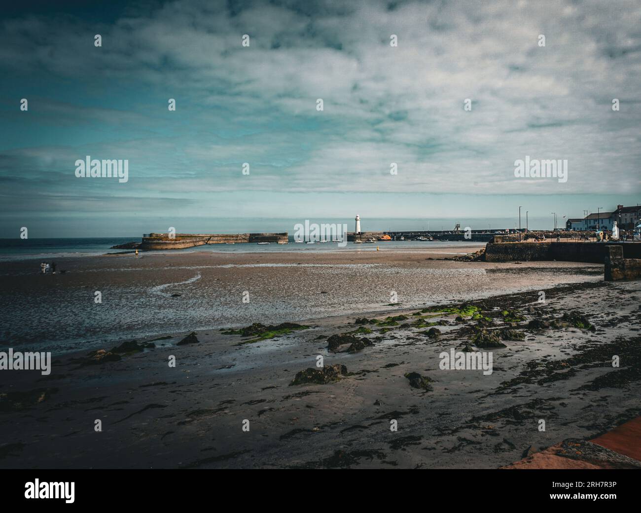 Der Strand in Donaghadee, County Down, Nordirland mit dem bekannten weißen Leuchtturm in der Ferne. Stockfoto