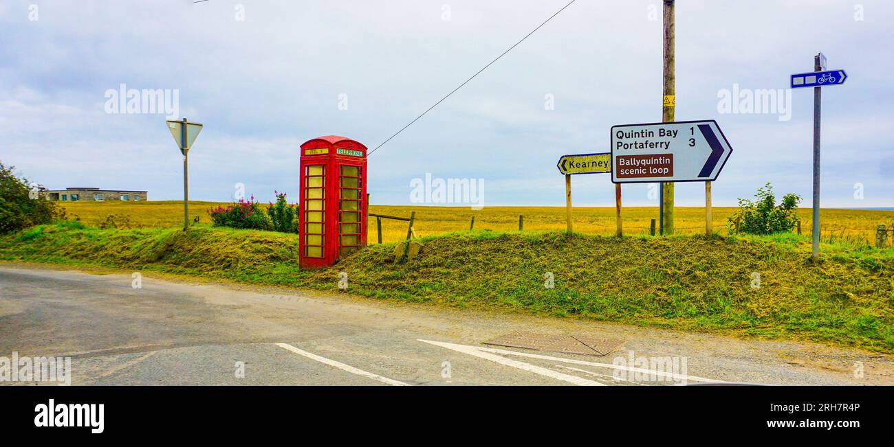 Entlang der Mourne Coastal Route, in County Down, Nordirland, eine alte, stillgelegte rote Telefonzelle in der Nähe der Straßenschilder für Kearney und Portaferry. Stockfoto