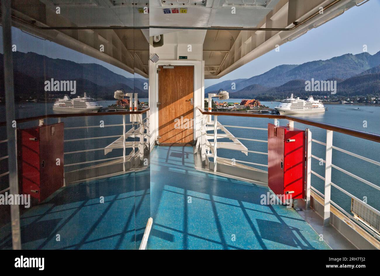 Reflexion über das Fenster des Kreuzfahrtschiffes Carnival Luminosa, verankertes Kreuzfahrtschiff und Hafen, mit Juneau Küste in der Ferne, Alaska. Stockfoto