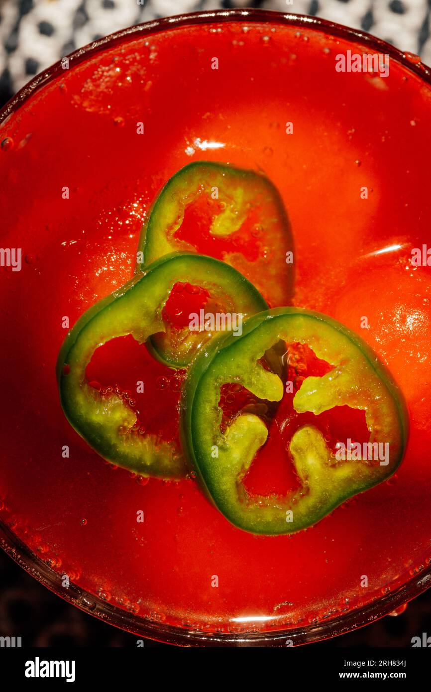 Blick von oben auf die Wassermelone jalapeño aqua Fresca mit Wassermeloneneis auf schwarz-weiß gemustertem Tuch in der Sonne Stockfoto