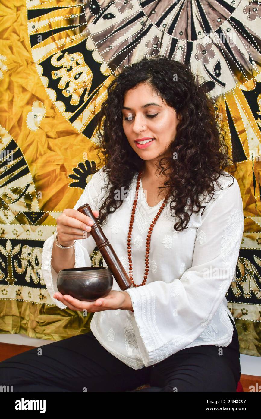 Eine Frau, die Meditation und Heilung mit einer tibetischen Gesangsschale praktiziert. Stockfoto