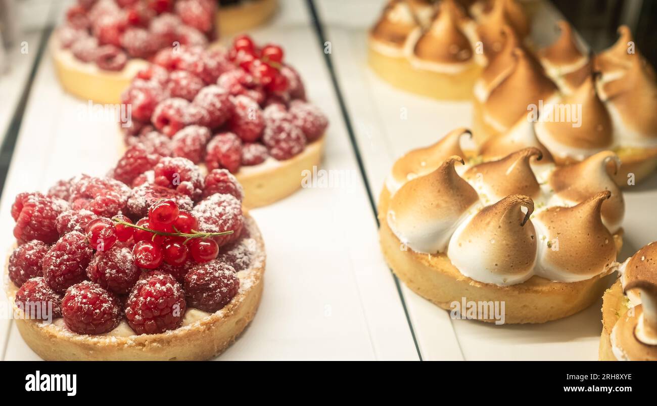 Verschiedene Beerentörtchen und Zitronen-Baiser-Torte mit Quark auf dem Tisch. Köstliches Gebäck. Leckere Passionsfrucht und Zitronentörtchen. Speisekonzept für Ruhe Stockfoto