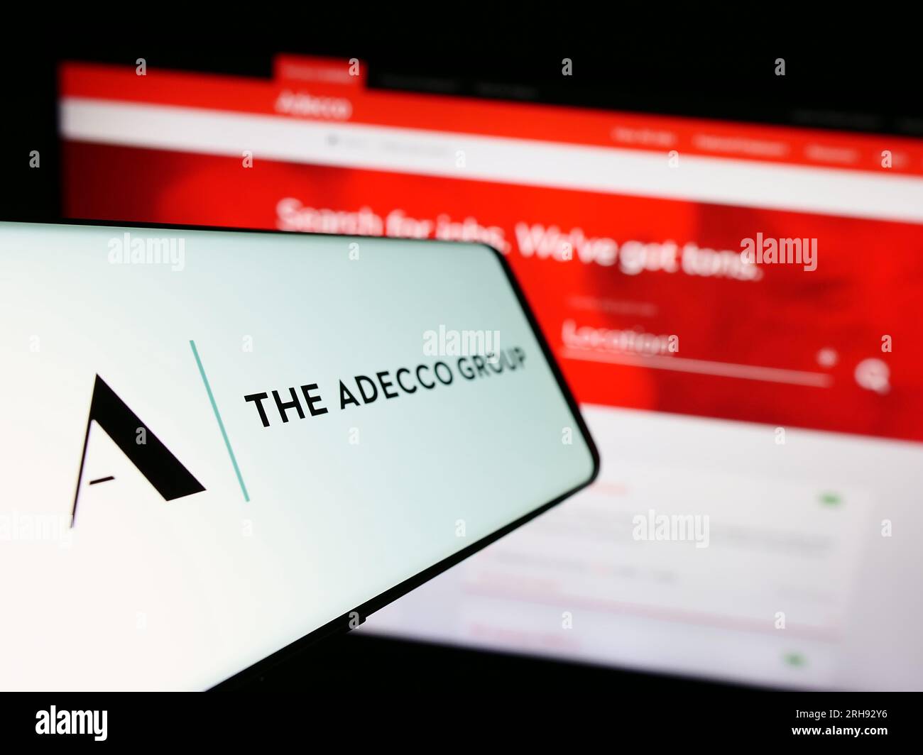 Mobiltelefon mit Logo des Personalunternehmens der Adecco Group AG auf dem Bildschirm vor der Website. Fokus auf die Mitte links des Telefondisplays. Stockfoto