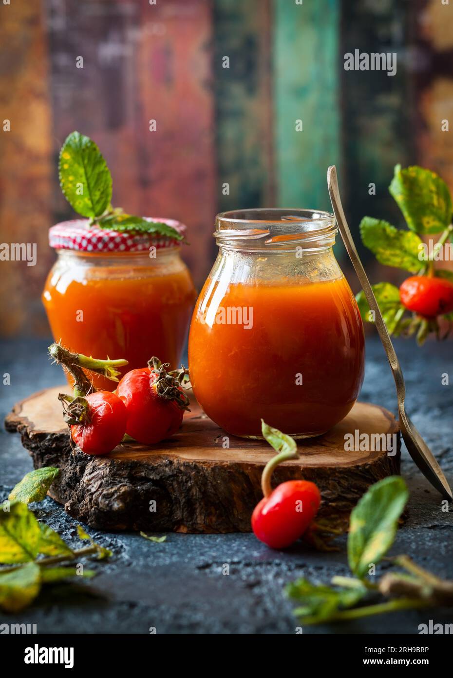 Rosenmarmelade im Glas mit frischen Beeren und Blättern Stockfoto