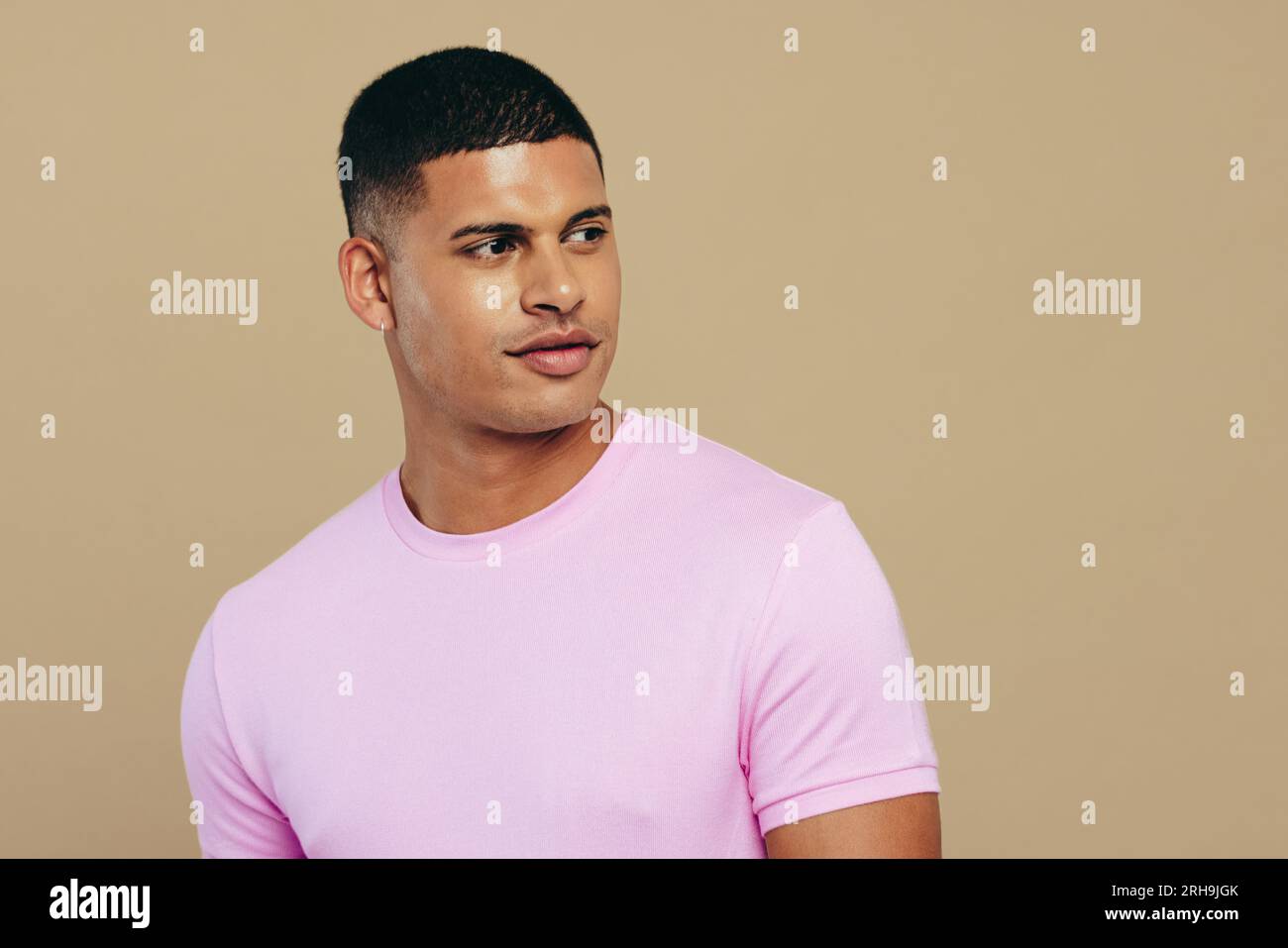 Selbstbewusster und gutaussehender junger Mann, der in einem Atelier steht und seinen glühenden und jugendlichen Hautton zeigt. Junger Mann, der seine Leidenschaft für Körperpflege und zeigt Stockfoto