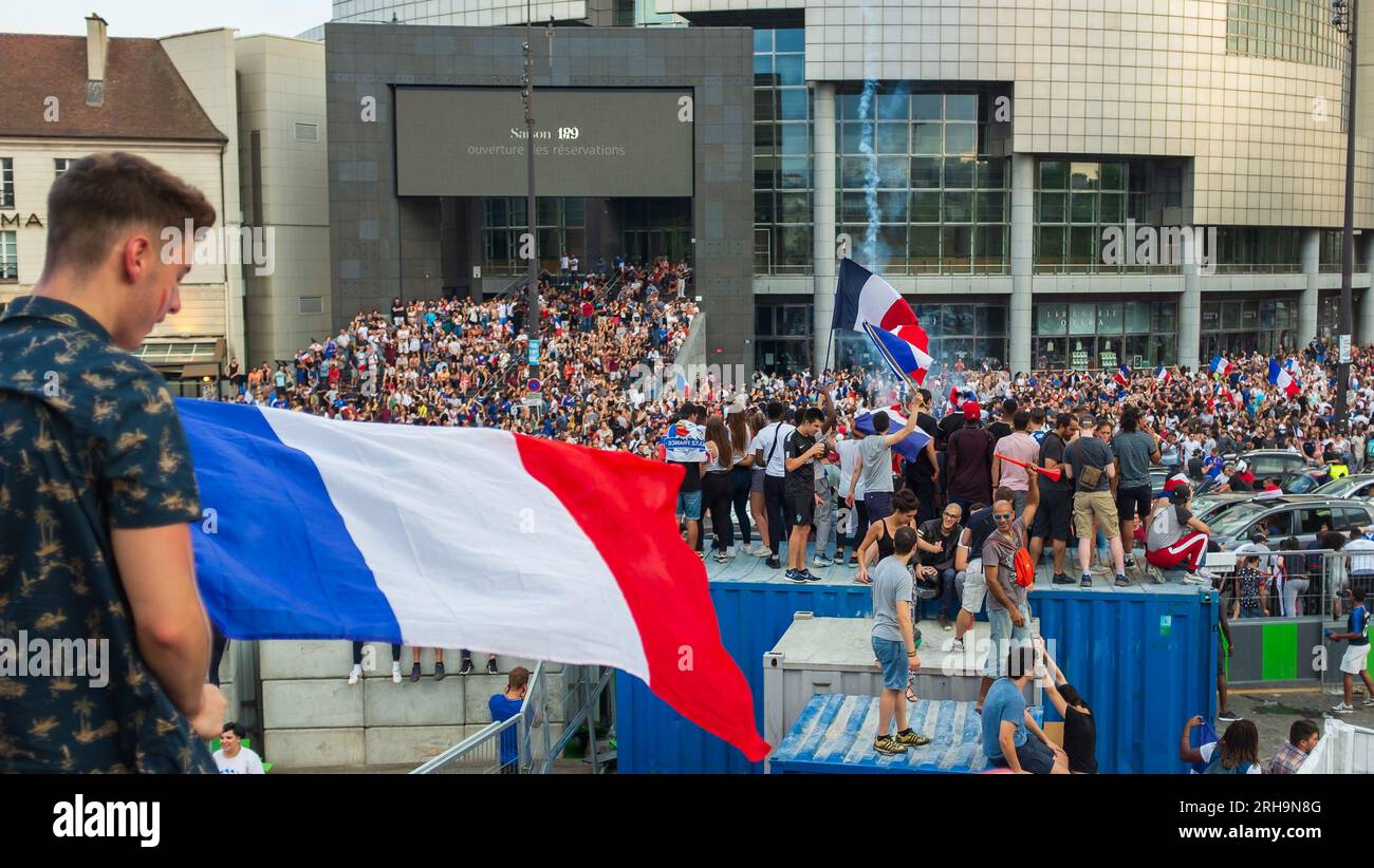 Paris, Frankreich, 2018. Ein Fußballfan, der auf der Julisäule mit Blick auf die Opéra Bastille steht, schwenkt eine französische Flagge, um die Fußball-Weltmeisterschaft zu feiern Stockfoto