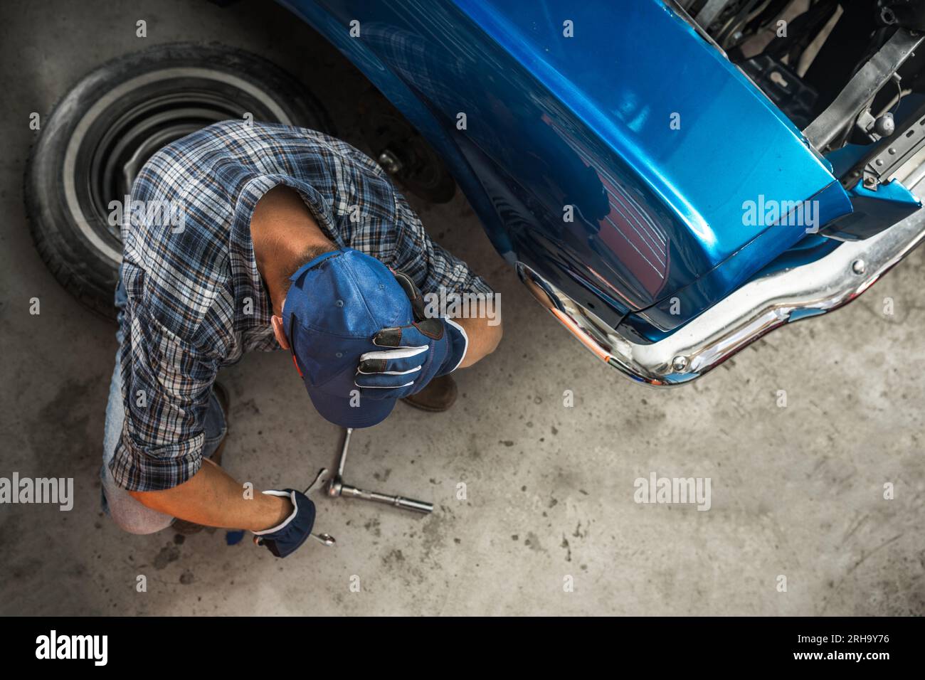 Verwüstetes Auto-Mechaniker-Sitzplätze neben Broken Blue American Muscle Classic Car Stockfoto