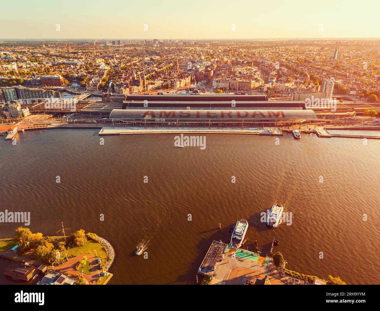 Luftaufnahme des Hauptbahnhofs von Amsterdam und des IJ Flusses in Amsterdam Niederlande bei Sonnenuntergang Stockfoto